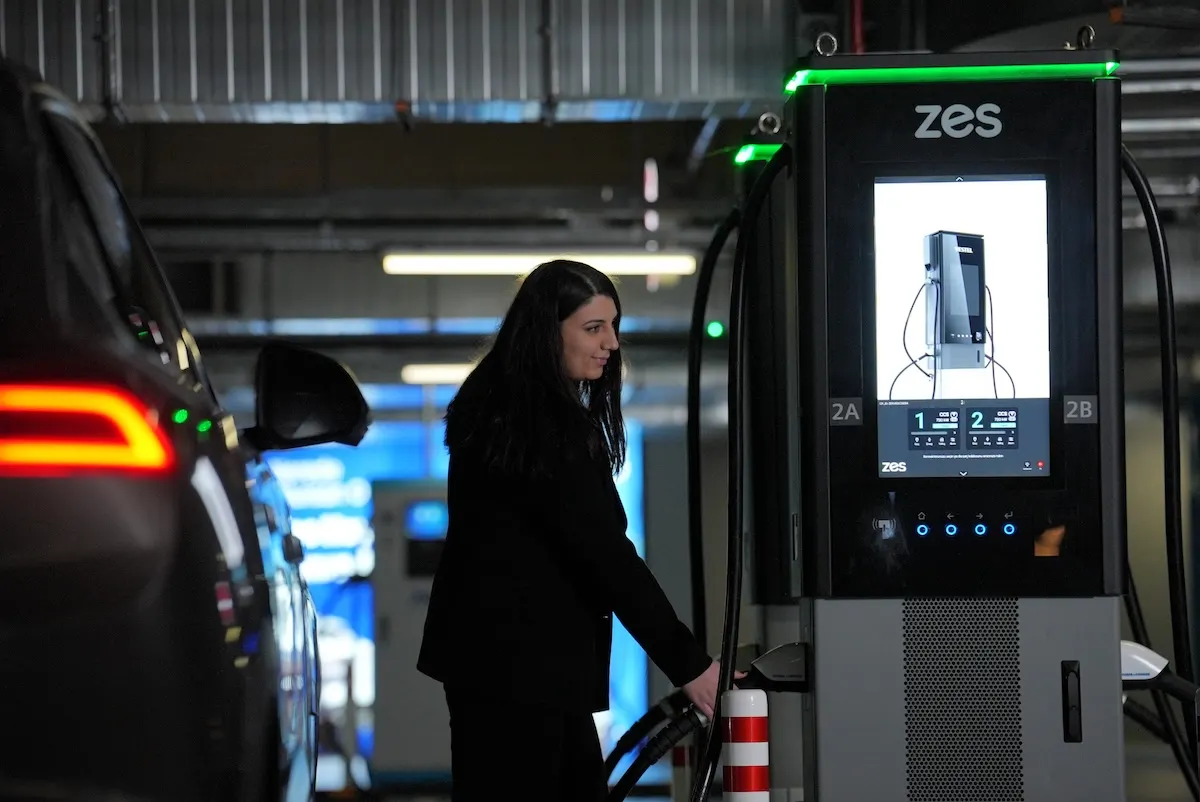 A driver plugging in the charging cable at a Zes 720 kW station